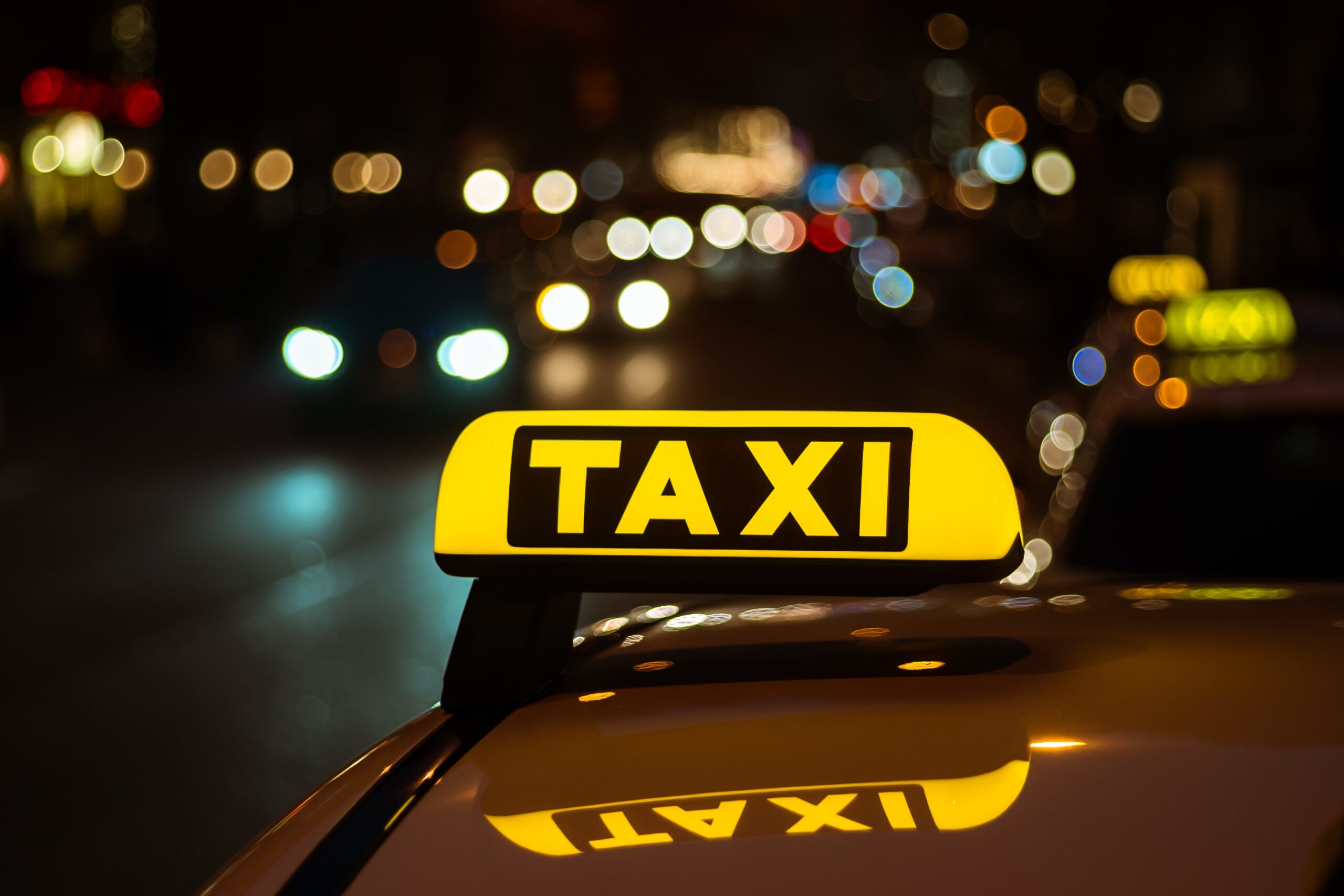 Yellow and black sign of Taxi placed on top of a car at night Porte coulissante en verre